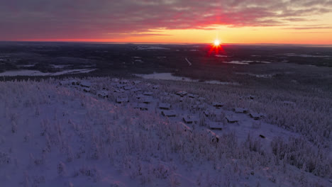 tomada panorámica de drones en órbita cabañas nevadas en el iso-syote cayó, puesta de sol en finlandia