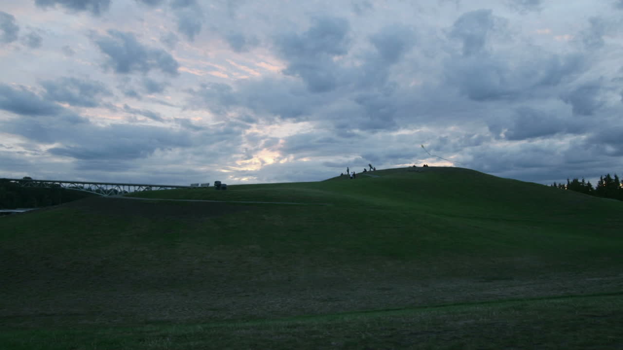 구름과 사람들이 매립지 뒤에서 하늘을 가로질러 움직입니다.