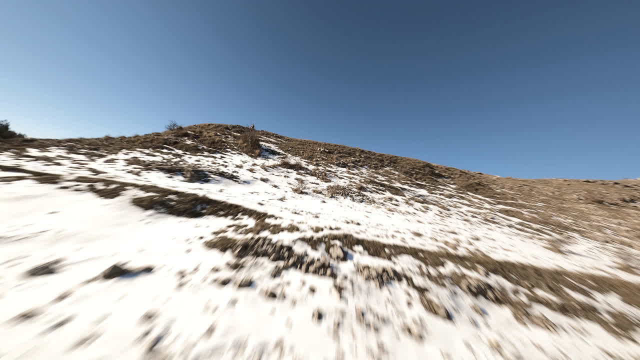 Flying close to a tree at high speed in a snow covered mountains landscape