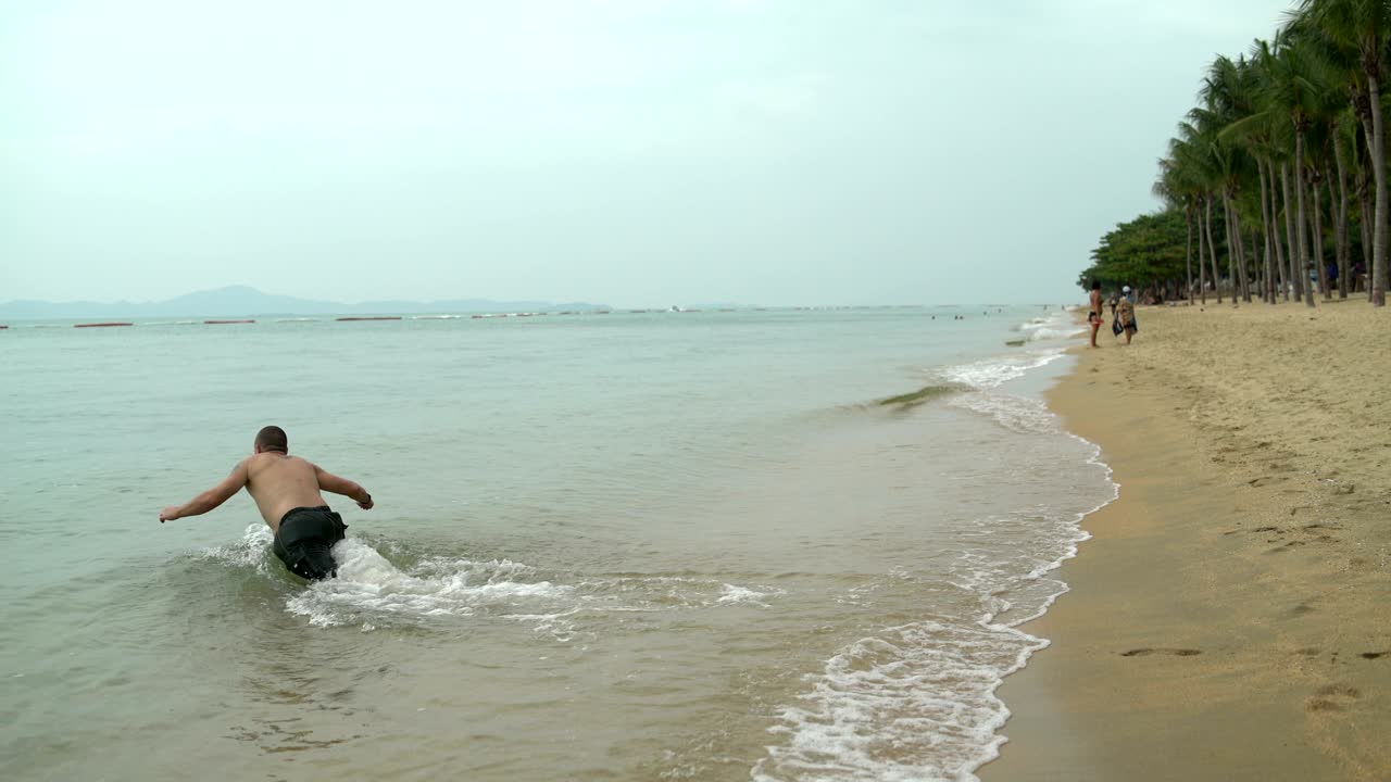 한 남자가 바다로 들어가서 잠수합니다.