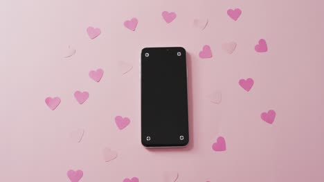 smartphone and paper hearts on white background at valentine's day