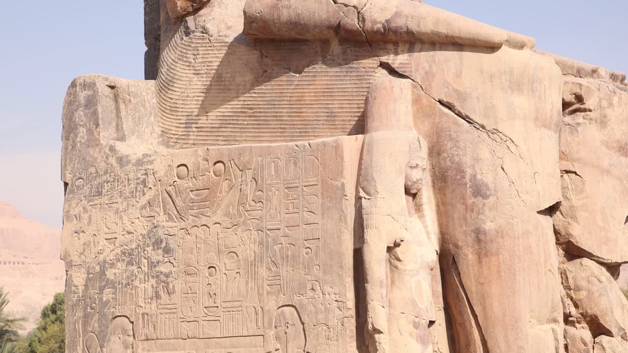 ruinas de la estatua gigante de faraón con montañas en el fondo en los colosos de memnon en luxor, egipto