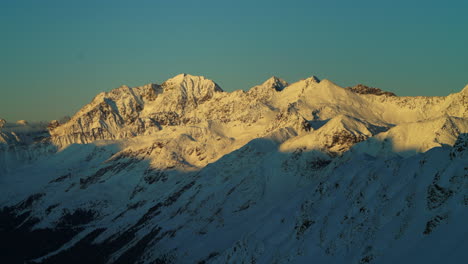 Toma-Amplia-De-Lapso-De-Tiempo-De-Las-Montañas-Nevadas-De-Los-Alpes-Durante-La-Puesta-De-Sol-Dorada-En-La-Noche---Hermosa-Vista-Panorámica-Desde-Arriba