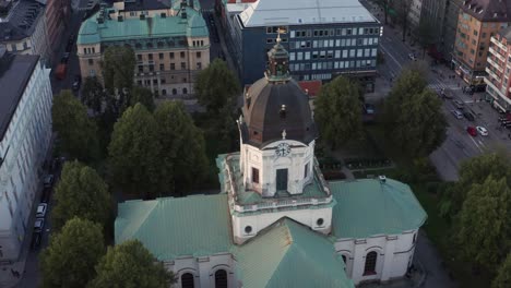 Drone-shot-of-Adolf-Fredriks-church-in-Stockholm,-Sweden-during-sunset-in-late-summer