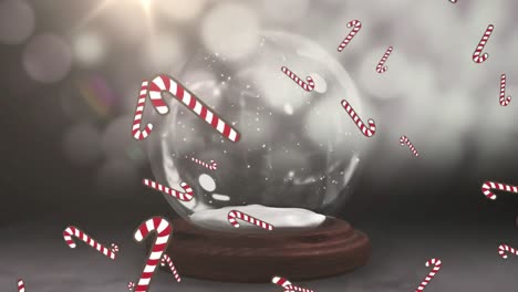 Candy-cane-icons-falling-over-shooting-star-spinning-around-snow-globe-against-grey-background