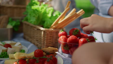 un delicioso almuerzo en un picnic de verano. manos irreconocibles toman fresas