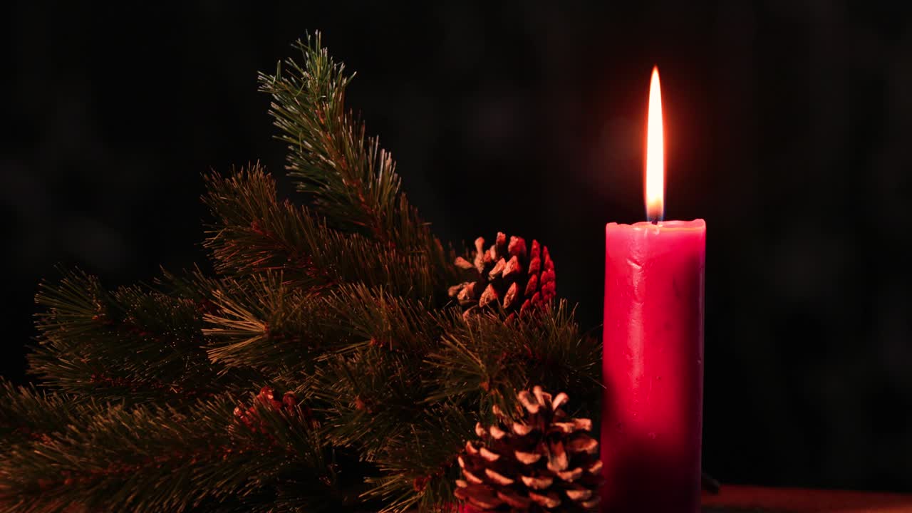 la vela de navidad arde en la mesa con conos de pino