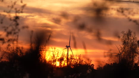 wind turbine under a blazing sunset with dramatic clouds in the background