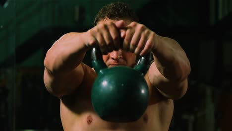 muscular man lifting kettle bell