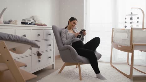 Wide-shot-video-of-caucasian-woman-in-advanced-pregnancy-browsing-ultrasound-scan-in-baby's-room.