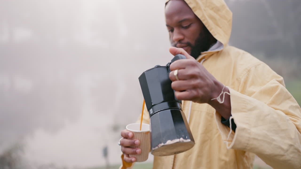 hombre negro, caminando y vertiendo café en la naturaleza