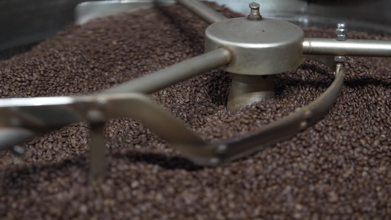 Metal stirring arms move roasted coffee beans evenly in the cooling tray