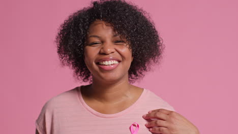 Studio-Portrait-Of-Smiling-Mid-Adult-Woman-Wearing-Pink-Breast-Cancer-Awareness-Ribbon-Against-Pink-Background-2