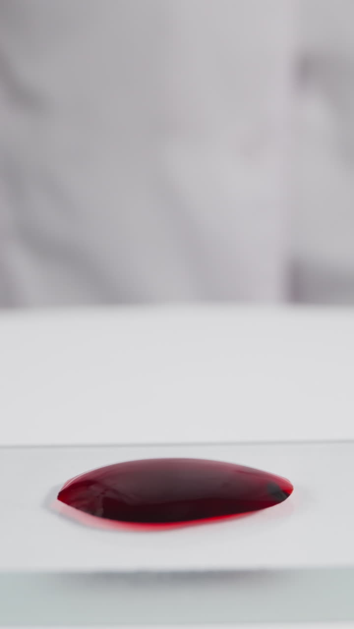 Frosted glass slide with blood drop and woman with pipette and loupe in laboratory slow motion. Probe lens footage of medical researching macro view