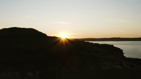 sunrise reveal behind silhouettes of cliffs over river drone