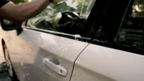 close up of a male washing a car wearing a black gloves with shampoo and sponge