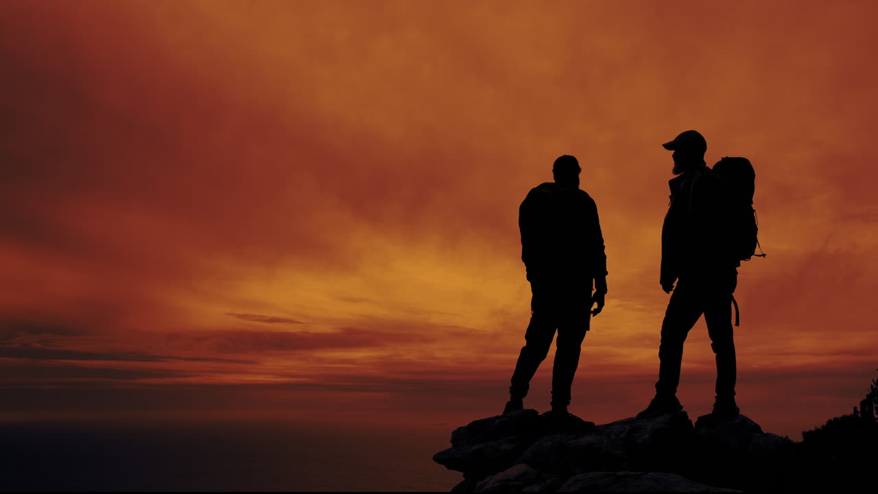 Two hikers silhouetted against a stunning sunset