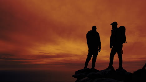 two hikers silhouetted against a stunning sunset