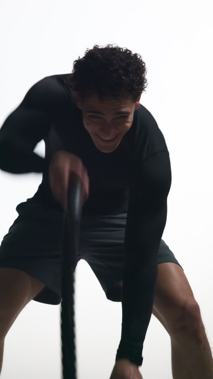Energetic Man Working Out with Battle Ropes in Studio