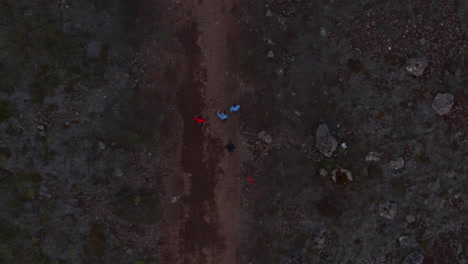 Overhead-view-birds-eye-of-four-people-friends-walking-rocky-desert-in-iceland-highlands.-Top-down-drone-view-of-tourist-walking-pathway-exploring-wilderness