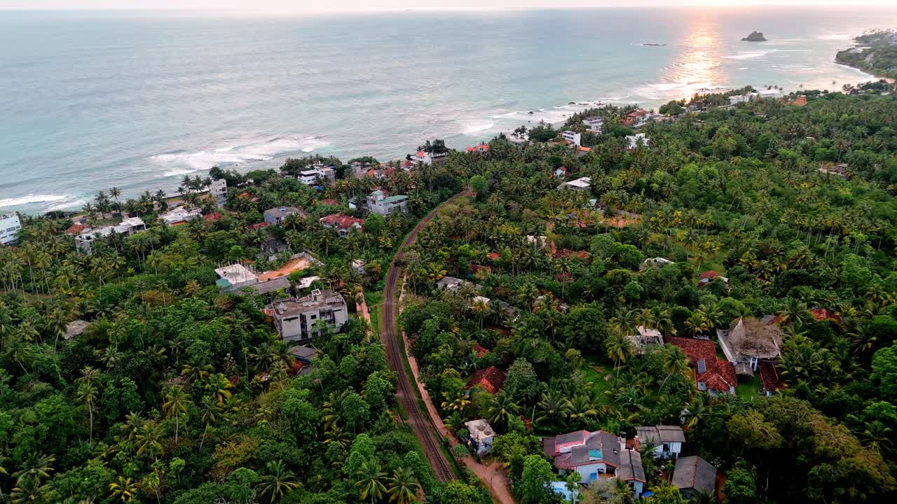 A stunning aerial drone shot capturing the coastal town of Weligama, Sri Lanka, bathed in warm golden light during sunset.