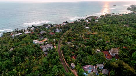 a stunning aerial drone shot capturing the coastal town of weligama, sri lanka, bathed in warm golden light during sunset.