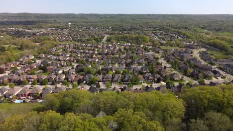 Aerial-shot-flying-toward-a-sunny,-summer-Hamilton-neighborhood-nestled-in-a-forest