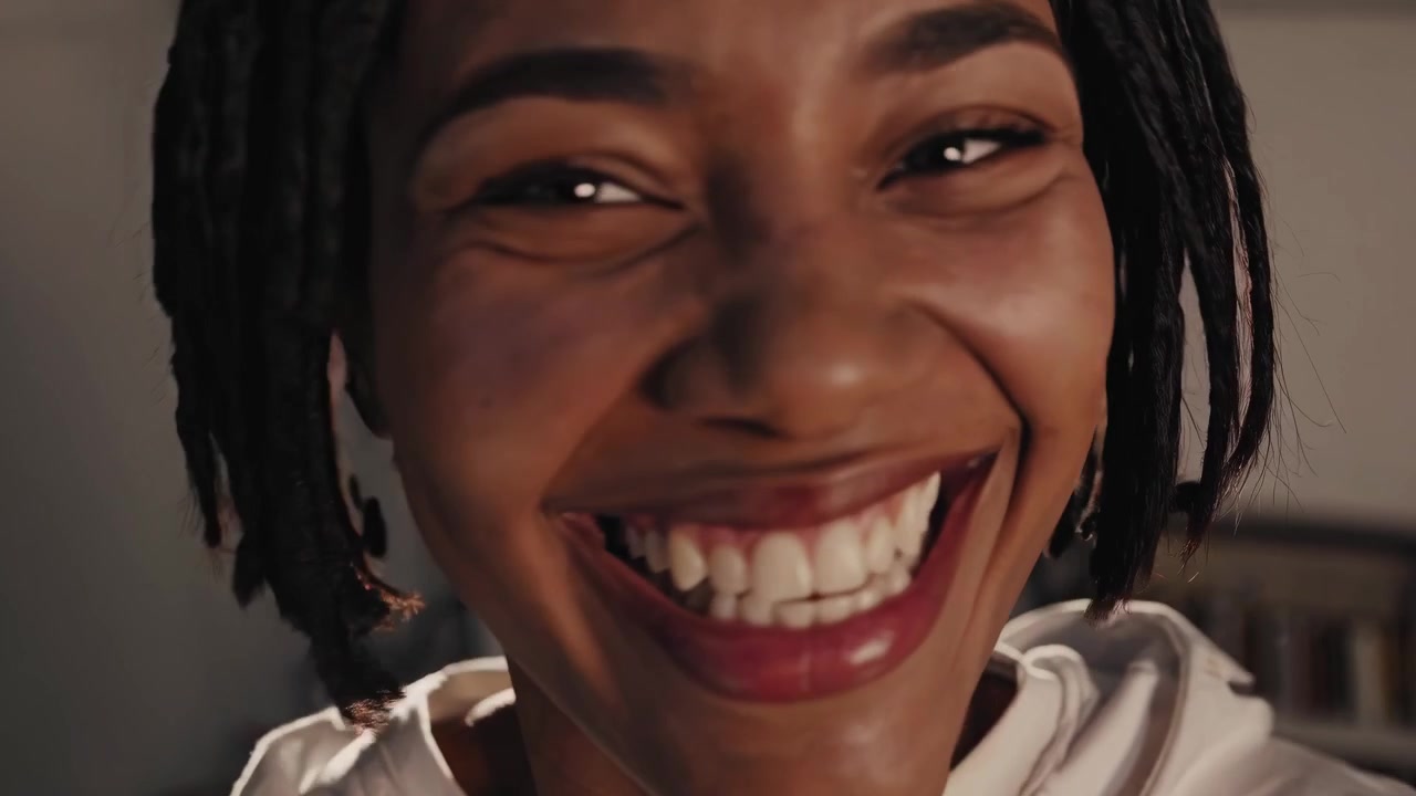 Primo piano di una giovane donna afroamericana felice che ride con bagliore dell'obiettivo