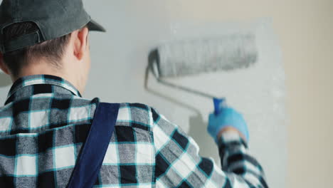 male builder paints wall with roller 2