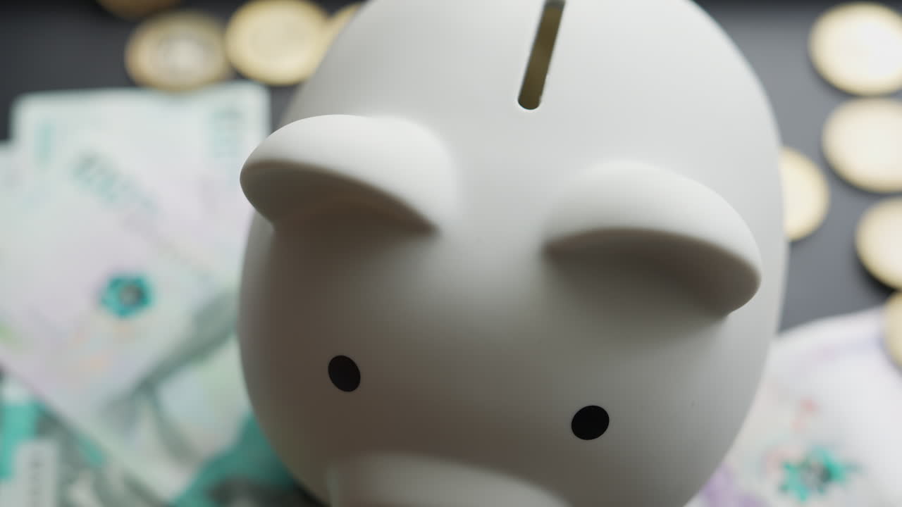 Detailed view of a white ceramic piggy bank surrounded by Colombian pesos, hinting at smart financial savings. Soft lighting creates a calm ambiance, emphasizing the coin slot and currency