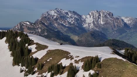 Espectacular-Vista-De-Una-Toma-Aérea-De-Una-Cabaña-En-La-Cima-De-La-Montaña-Nevada-En-Amden-Sentis,-Suiza