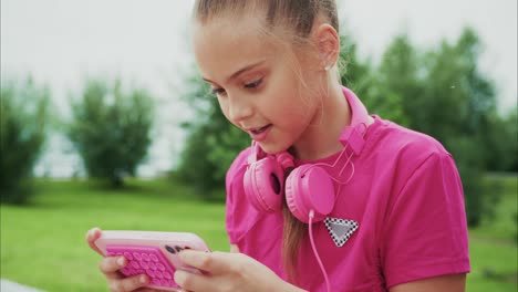 a young girl enjoying her time outdoors while using a smartphone with headphones - capturing the joy of play and technology in a natural setting