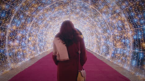 girl walks through a beautiful tunnel of christmas lights back view slow motion
