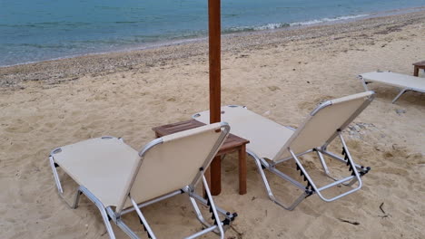 empty sunbeds and hatched roof umbrellas on the first line of a sandy beach at the sea