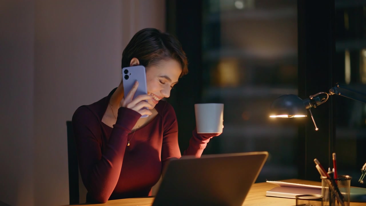 Happy woman phone call holding coffee cup dark evening office. Night work break