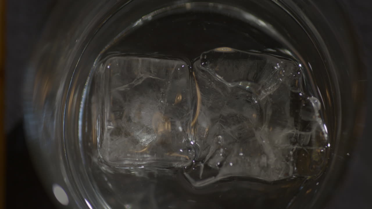 유리잔에 얼음 조각이 있는 보드카 한 잔을 내려놓는 바텐더 - 위쪽 전망