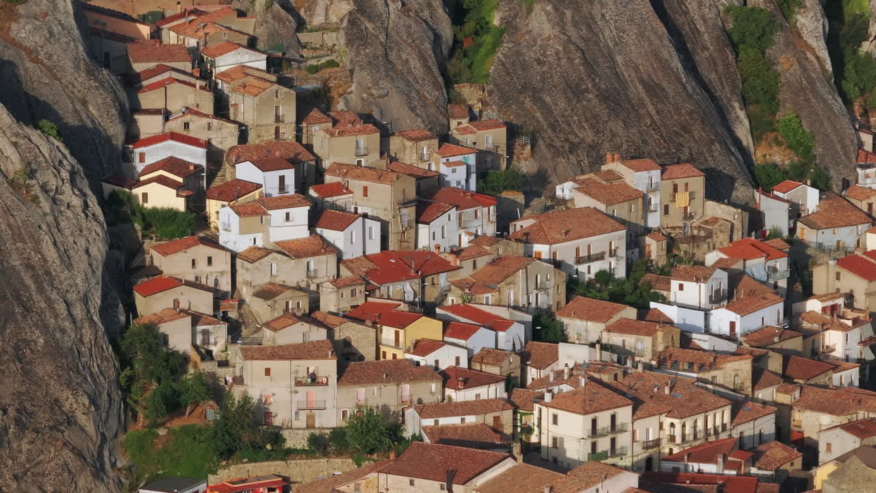 Aerial drone of Pietrapertosa, Italy—mountain village built into rocky peaks, terracotta roofs, sweeping valley views. Ideal for travel, tourism, culture, and cinematic landscape stock footage