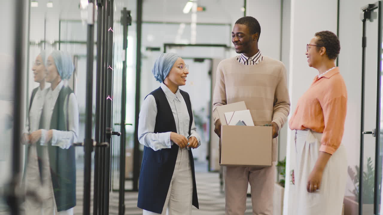 Businesswoman And Muslim Businesswoman Talk To Young Man At Office Door