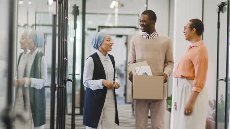 businesswoman and muslim businesswoman talk to young man at office door