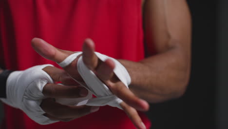 primer plano en tiempo real de un boxeador masculino envolviendo las manos con vendajes protectores antes de un partido de boxeo o sesión de entrenamiento 2