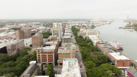 Drone-of-Savannah-Georgia-riverfront-area-along-the-river-with-cars-and-boats-on-an-overcast-day-with-Talmadge-Memorial-Bridge