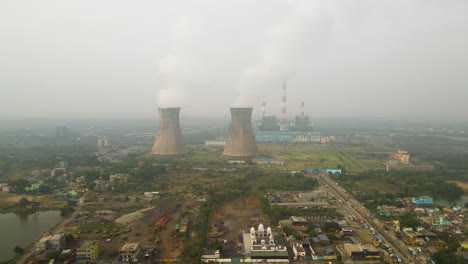 aerial drone capture of factories in india, focusing on dense smoke rising from their chimneys.