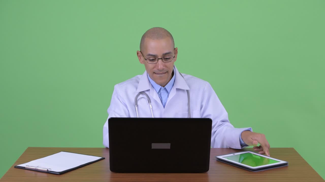 feliz hombre multiétnico calvo médico en el escritorio de la oficina