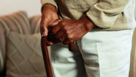 senior man getting up from sofa with walking stick