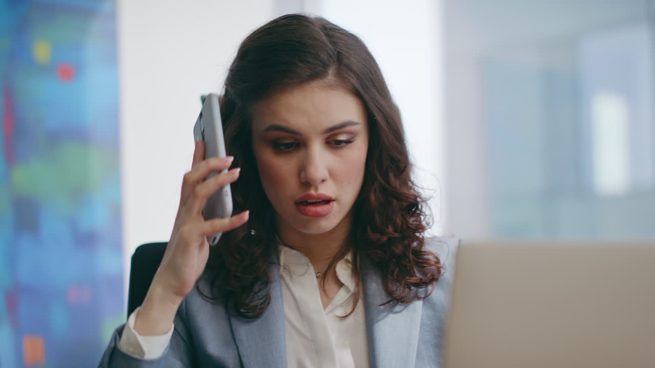 mujer nerviosa contestando una llamada telefónica sentada en la oficina de cerca. gerente de chica ocupada