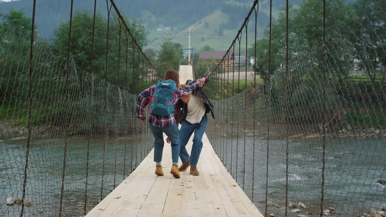 mochileros de pie puente del río en las montañas caminata. pareja feliz jugar alrededor.