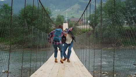 backpackers standing river bridge on mountains hike. happy couple play around.