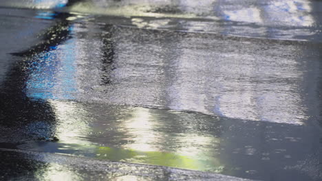 silhouette reflection on rain puddles of a person walking across the asphalt road in tokyo, japan