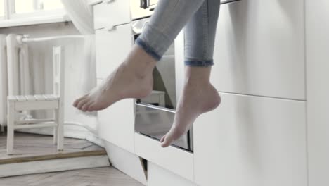 woman relaxing with feet dangling from kitchen counter