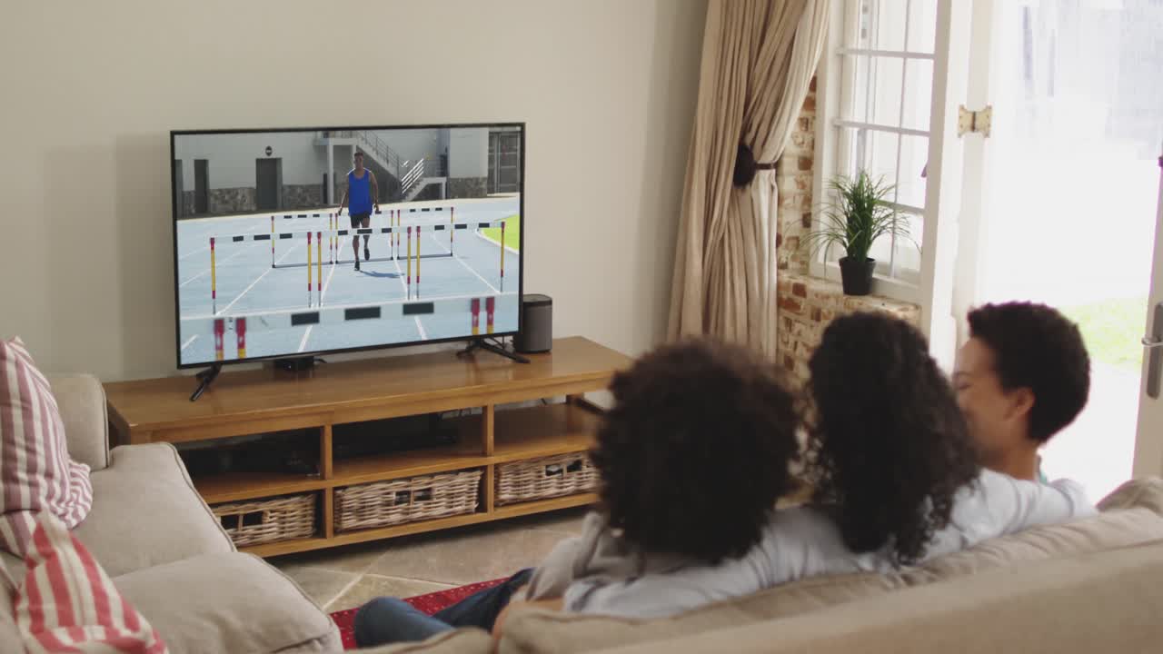 Composizione di famiglia felice seduta insieme a casa che guarda un evento di atletica leggera di corsa in TV.